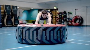 YMCA student pushing a tire across a gymnasium