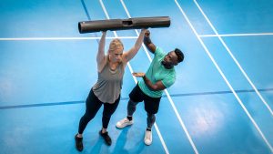 Personal trainer assisting a client on a gym floor