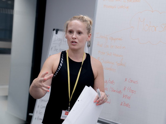 YMCAfit Tutor Hannah teaching a theory class with a whiteboard behind her