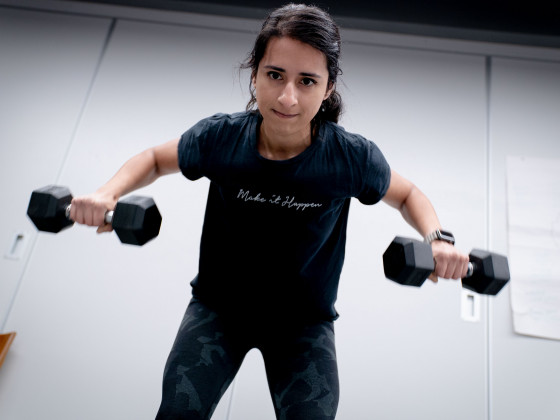 Woman exercising in a classroom ith a pair of dumbells